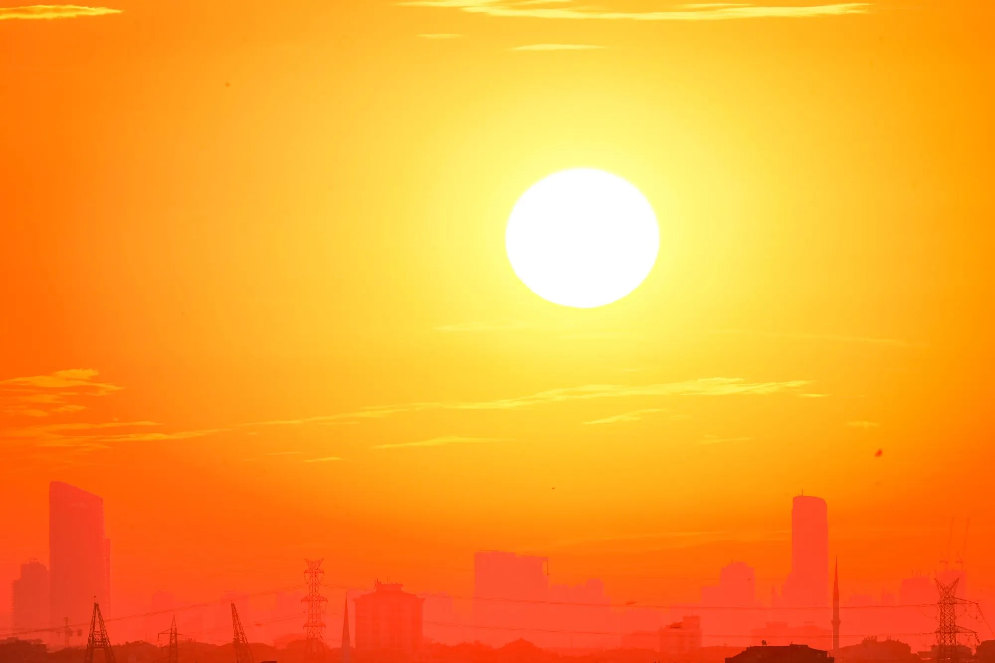 Tief stehende, glühende Sonne über einer dunstigen Stadt-Skyline
