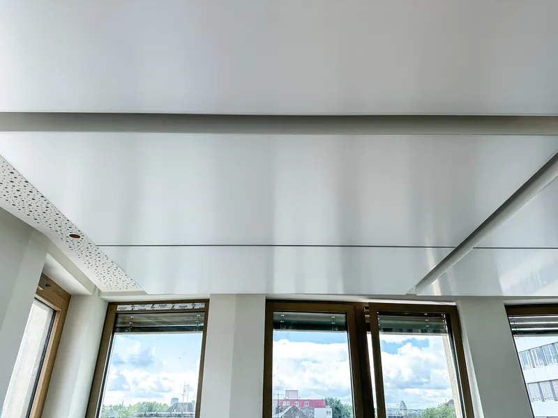 Untersicht des Lichthimmels aus interpanel Klimaleuchten mit Randfries aus gelochter Akustik-Gipskartondecke und Fensterband