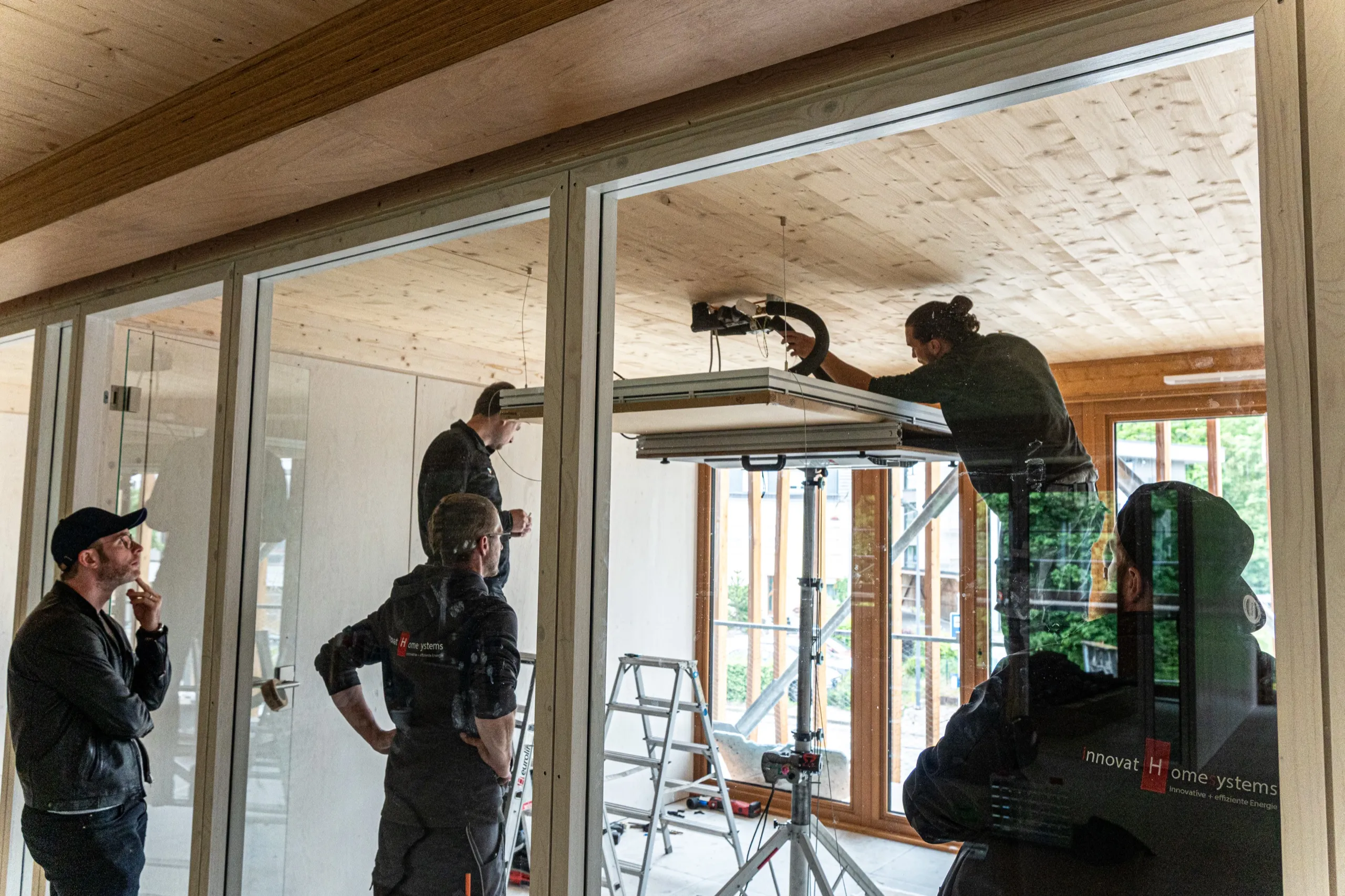 Monteur-Team pendelt ein interpanel Deckensegel von der Holzdecke ab
