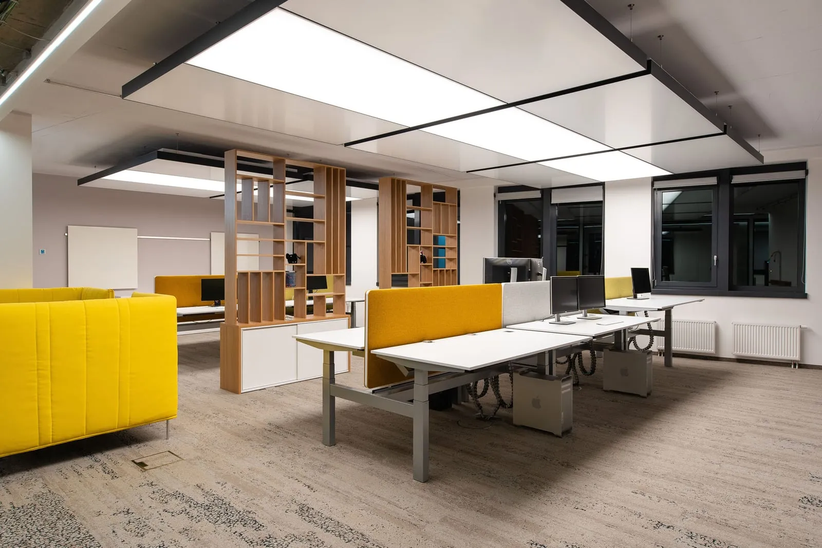 Modernes Großraumbüro mit leuchtenden interpanel Deckensegeln über Arbeitsplätzen und einem Lounge-Bereich
