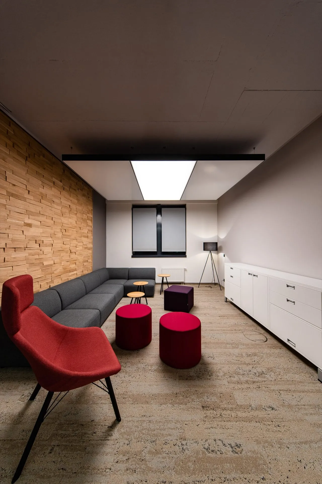 Premium-Loungeraum mit leuchtendem interpanel Deckensegel über grauem Sofa und Holzwand