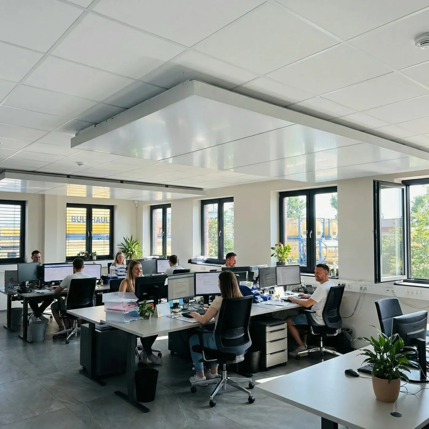 Bulkhaul: dicht belegtes Büro im laufenden Betrieb, temperiert über das interpanel Deckensegel, Tankcontainer durch die Fenster sichtbar