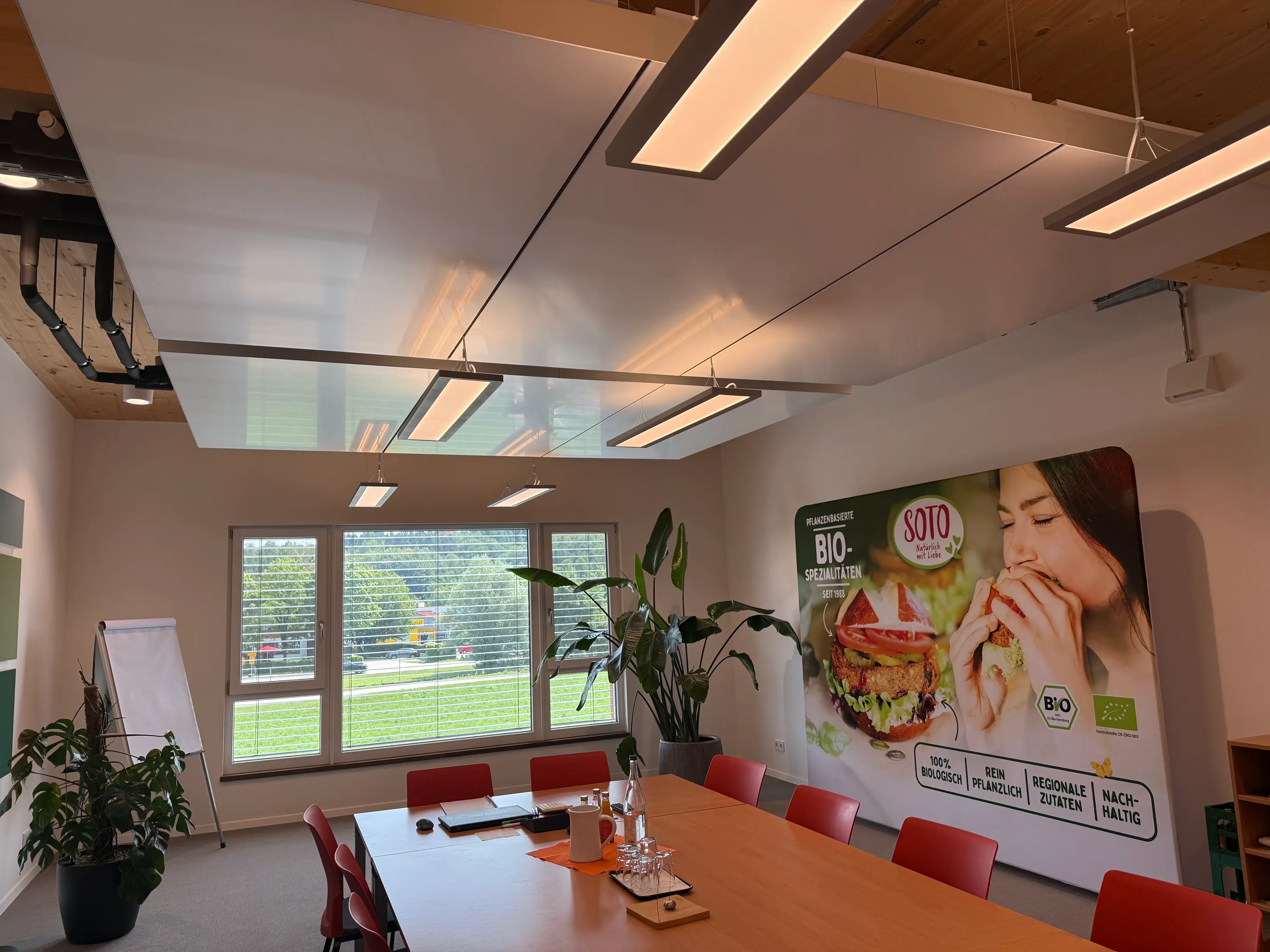 Besprechungsraum bei SOTO in Bad Endorf mit interpanel Klimapanels und Linearleuchten unter einer Holzdecke