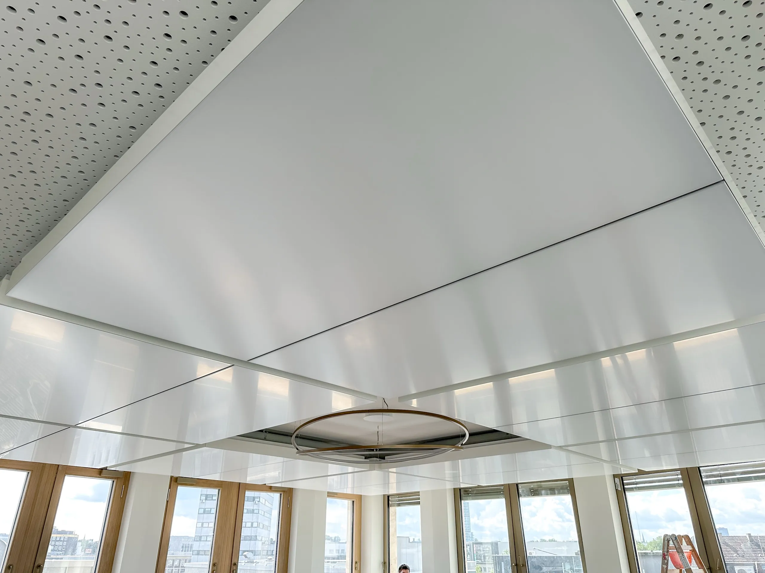 Untersicht der HCL-Klimadecke der Sparkasse Bochum mit mittiger ringförmiger Akzentleuchte zwischen den Deckensegeln