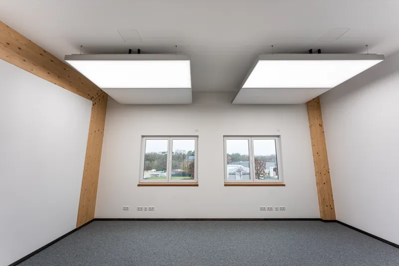 Blick durch das Holzportal in einen Büroraum mit zwei interpanel Klimaleuchten