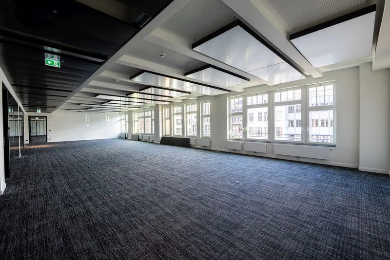 Weiträumige Bürofläche der Kaisergalerie Hamburg mit Reihen abgehängter interpanel Klimapanels, Fensterfront zum Innenhof und dunklem Teppichboden.