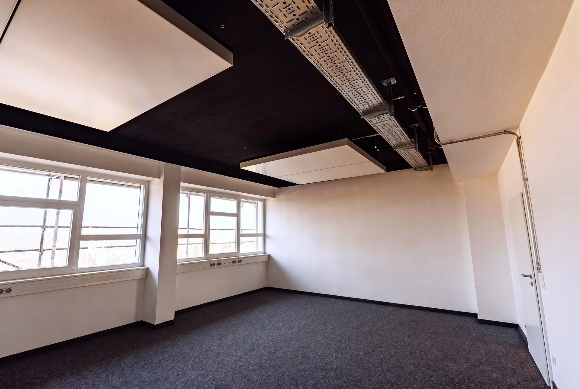 Zwei interpanel Deckensegel entlang der Fensterfront unter der schwarzen Decke